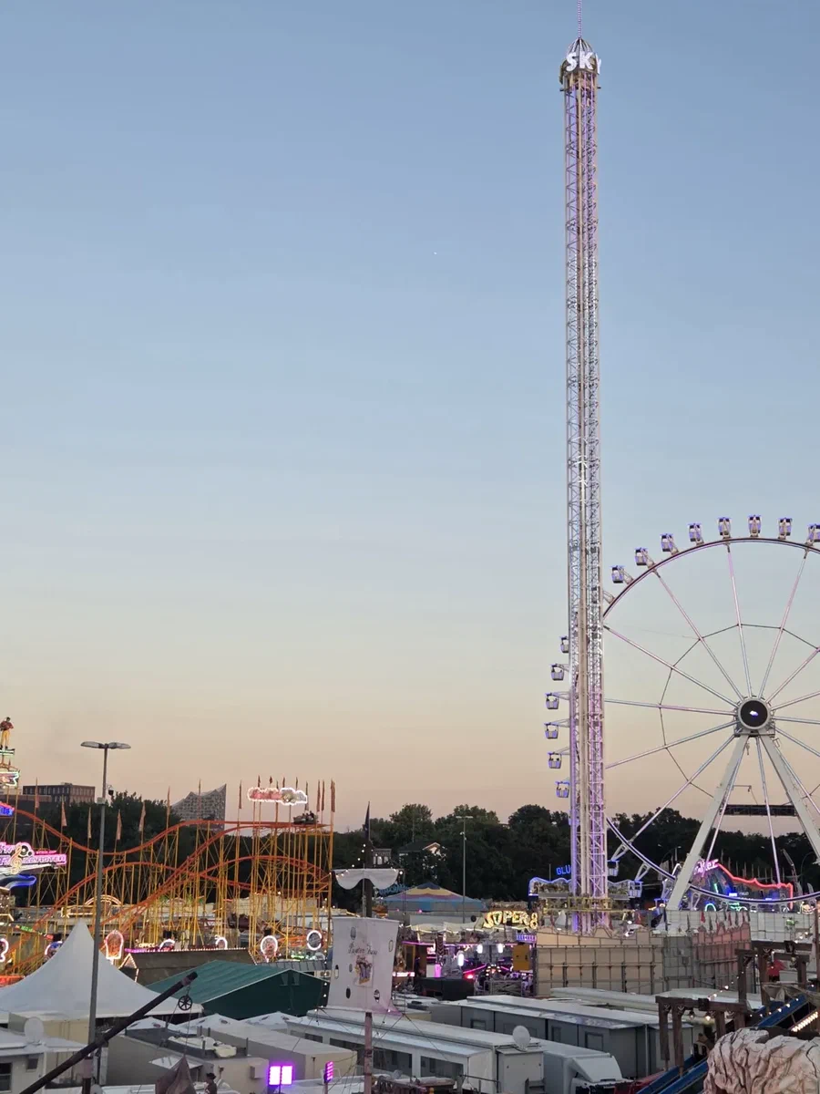 Blick vom Millerntor auf den Hamburger Dom im Abendlicht mit Kettenkarussell und Riesenrad